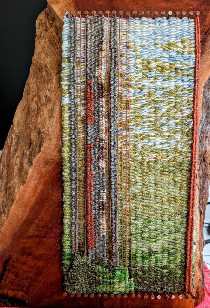 A woven tapestry of greens, blues, browns and grey against a red gum timber block.
