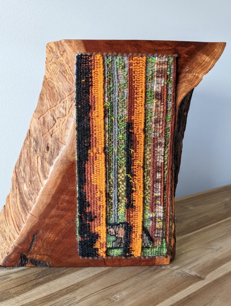 a finished tapestry of redwoods and a bear against a red gum timber block. 